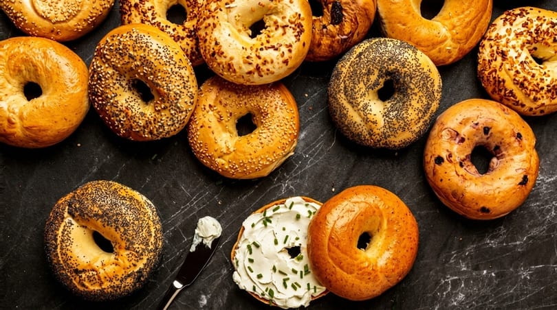 Assortment of bagels with various toppings, including one with cream cheese and chives.