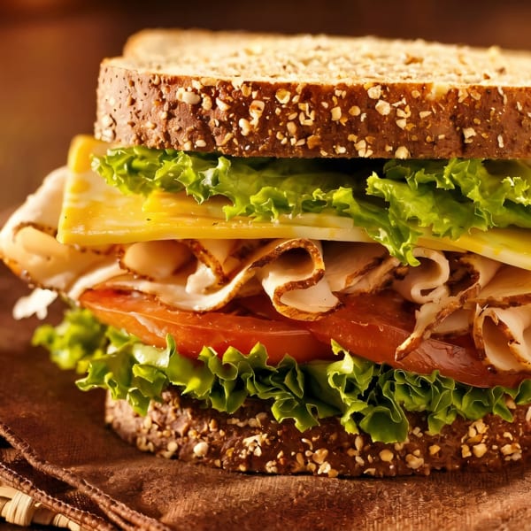 A delicious turkey and cheese sandwich on whole wheat bread with lettuce and tomato.
