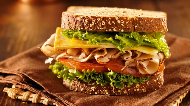 A delicious turkey and cheese sandwich on whole wheat bread with lettuce and tomato.